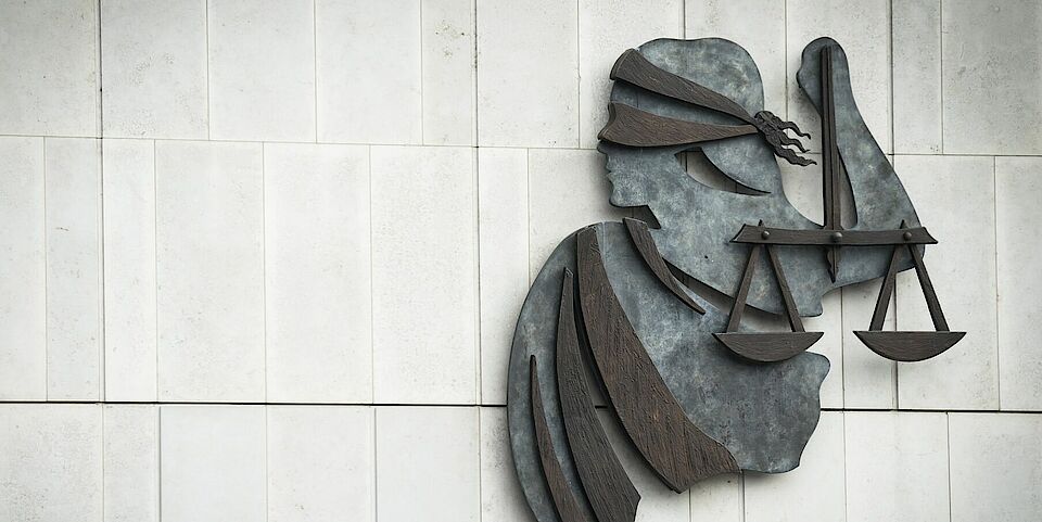 Modern wall sculpture of Lady Justice with blindfold and scales